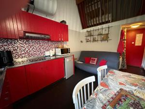 - une cuisine avec des placards rouges, une table et un canapé dans l'établissement Cocooning Auvergnat, à La Bourboule 10 autres photos