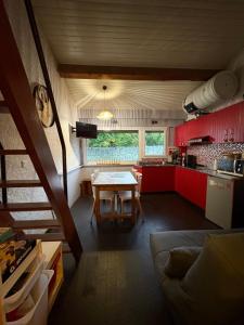 - une cuisine avec des placards rouges et une table dans l'établissement Cocooning Auvergnat, à La Bourboule