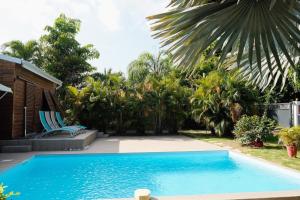 a swimming pool in a yard with chairs and trees at Villa Bel Arbre in Saint-François