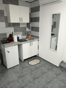 a kitchen with white cabinets and a tile floor at Studio Apartman Treće Nebo in TrÅ¡iÄ‡ +4 photos