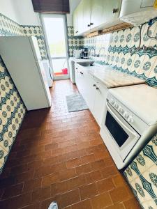 a kitchen with white appliances and a tile floor at Faro Family Apartment in Faro