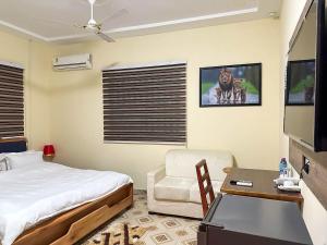 a bedroom with a bed and a desk and a tv at Senalli Hotel in Koforidua