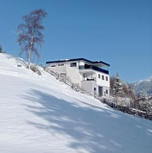 a house on top of a snow covered hill at Panorama Wildgrat in Wenns