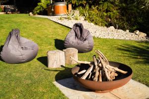 two bean bags sitting on the grass next to a fire at Hightide River Escape -with Outdoor Bath in Hokitika +40 photos
