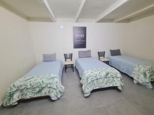 drie bedden in een kamer met stoelen en een bord bij Hostal Casa Gavilán 