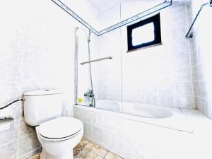 a white bathroom with a toilet and a bath tub at Studio com vista para Rua da Oura - Albufeira in Albufeira