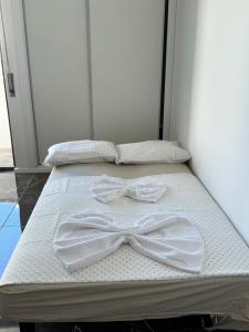 two beds with white sheets and a bow tie on them at Studio com vista para Rua da Oura - Albufeira in Albufeira