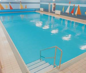 a large swimming pool with blue water and stairs at Ferienwohnung Reede 19 in Butjadingen