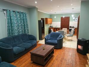 a living room with a couch and two chairs and a table at Villa De Lyden in Lydenburg