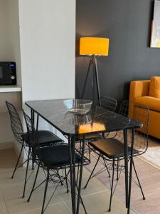 ein schwarzer Esstisch mit Stühlen und einer gelben Lampe in der Unterkunft A2I - 33rd Floor SkyCity Residence With Skopje View in Skopje + 13 Fotos