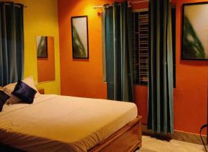 KhandagiriHotel O Housefull Residency的一间卧室配有橙色墙壁和蓝色窗帘的床