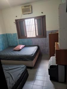a small room with two beds and a window at Casa Tupy próxima a praia e restaurantes in Praia Grande