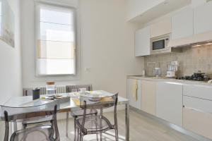 kuchnia z białymi szafkami oraz stołem i krzesłami w obiekcie UR-NEST Vestri - Golden Suite w Bolonii