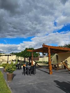 eine Terrasse mit Tischen und Stühlen und einer hölzernen Pergola in der Unterkunft Santa Catalina Hotel in San Antonio de Areco