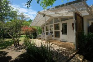 a porch of a white house with a patio at Piesang Valley Cottage Djungle in Plettenberg Bay