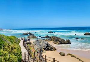 a beach with a wooden fence and the ocean at Piesang Valley Cottage Djungle in Plettenberg Bay +12 photos