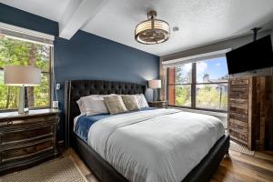 a blue bedroom with a bed and two windows at Hot tubs and pool -Looping shuttle- Cozy fireplace in Steamboat Springs +20 photos