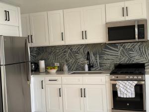 a kitchen with white cabinets and a stainless steel refrigerator at Egret at Galley Bay View in Five Islands Village