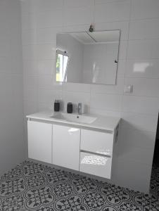 ein weißes Badezimmer mit Waschbecken und Spiegel in der Unterkunft Casa de São João in São João