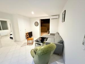 una sala de estar con un sofá y una silla en Logement catalan, en Perpiñán