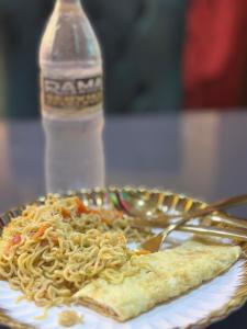 ein Teller Nudeln mit einer Gabel und einer Flasche Wasser in der Unterkunft Rama Garden Hotel ,Lafe Rd, Akure in Akure