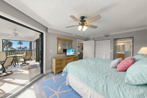 a bedroom with a bed and a television and a balcony at Pointe Santo B25 in Sanibel +79 photos