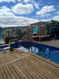 a pool with a wooden deck and a pergola at Mini House Park in Campo Alegre