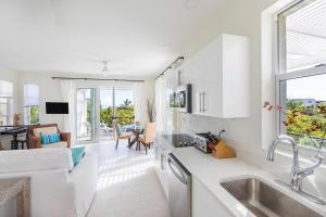 a kitchen with white cabinets and a living room at Wyakha 2 Ocean View in Long Bay Hills