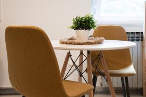 - une table avec deux chaises et une plante en pot dans l'établissement Cozy Studio w Floor Heating & King Size Bed, à Sesvete 7 autres photos