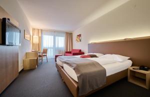 ein Hotelzimmer mit einem großen Bett und einem Stuhl in der Unterkunft Hotel Momentum in Anif