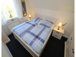 a bedroom with a bed with a plaid blanket and pillows at Ferienhaus Seeschwalbe in Dornumersiel in Dornumersiel
