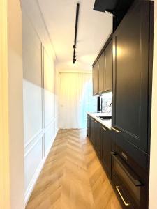 cocina con armarios negros y suelo de madera en Stylish Modern-Victorian Apartment with Balcony, en Staré Mesto
