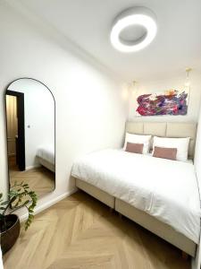 Un dormitorio con una cama blanca y un espejo. en Stylish Modern-Victorian Apartment with Balcony, en Staré Mesto