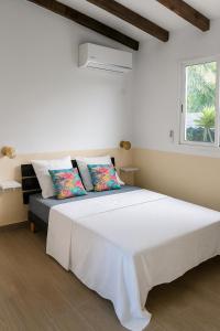 a white bedroom with a large white bed and a window at Fleur de Lys 2 in Petit-Bourg