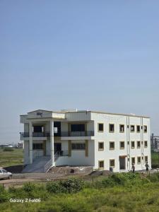 un edificio blanco en medio de un campo en Shrimant Executive Lodging, en Jejūri