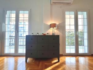 Una cómoda con una lámpara encima en una habitación con ventanas. en Hellenic Pleasure Residences, en Atenas