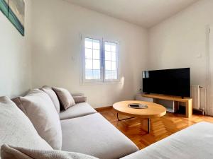 Una sala de estar con un sofá y un televisor. en Hellenic Pleasure Residences, en Atenas
