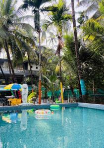 une piscine avec des palmiers dans un complexe hôtelier dans l'établissement Green Waves Resort, à Nagaon