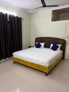 uma cama com almofadas roxas num quarto em Green Waves Resort em Nagaon mais 6 fotografias