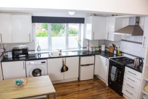 eine Küche mit weißen Schränken und einem Herd mit Backofen in der Unterkunft Apartment on high street in Saltdean