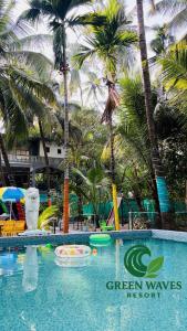 une piscine dans un complexe hôtelier Green Waves avec des palmiers dans l'établissement Green Waves Resort, à Nagaon