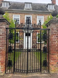 an ornate iron gate to a brick house at The Grange, Northill in Northill