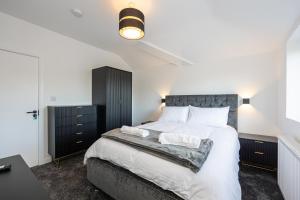 Un dormitorio con una cama grande con sábanas blancas. en Modern 5-Bed Home EV City Centre 10 min, en Mánchester