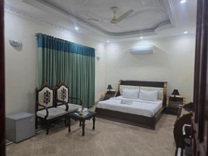 a bedroom with a bed and a couch and a chair at Executive Galaxy Guest House Islamabad in Islamabad