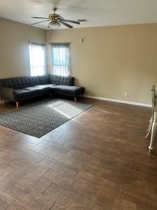 a living room with a black couch and a ceiling fan at West Phoenix Value Room 4 Bennet in Phoenix +2 photos