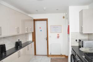 a kitchen with white cabinets and a white door at JMG HOUSE - Quality Rooms in West Bromwich +24 photos
