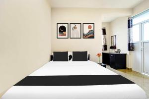 1 dormitorio con 1 cama blanca grande y cuadros en la pared en Super Collection O Saravanampatti, en Coimbatore