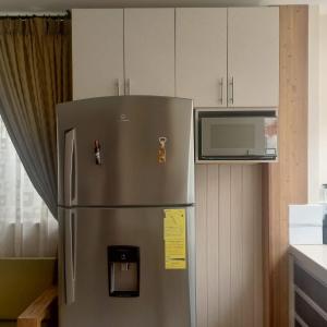 un frigorifero in acciaio inossidabile in una cucina con forno a microonde di Departamento de 2 dormitorios en la Victoria, cerca de las Universidades con garaje gratis a Ibarra