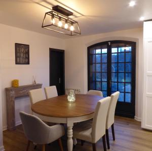 a dining room with a wooden table and white chairs at Villa Gustavine - Maison d'Architecte in Ger