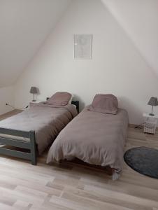 deux lits dans une chambre aux murs blancs et au parquet dans l'établissement Le Haut de Clarques, à Clarques
